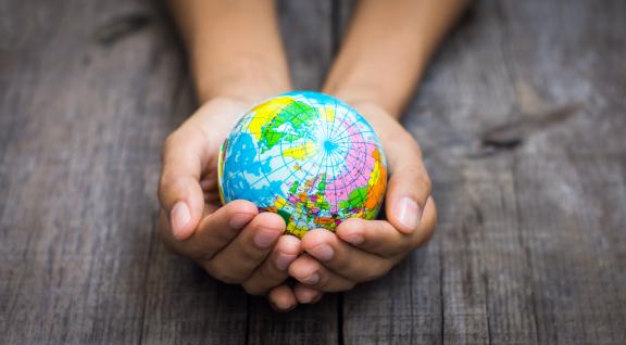 Handen houden kleine wereldbol vast